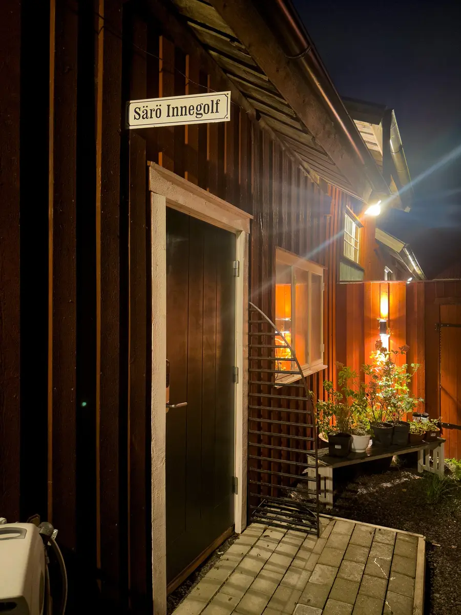 Ingången till Särö Innegolf i ett rött trähus, upplyst en mörk kväll.